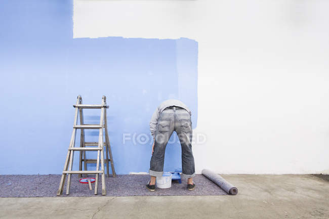 Vista trasera de la pared de pintura del hombre por color azul - foto de stock