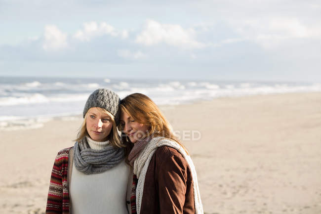 Mujeres abrazándose en la playa - foto de stock
