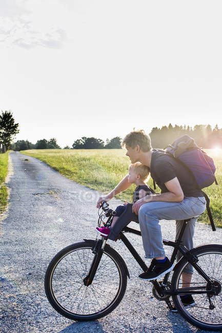 Отец и маленькая дочь катаются на велосипеде вместе — стоковое фото