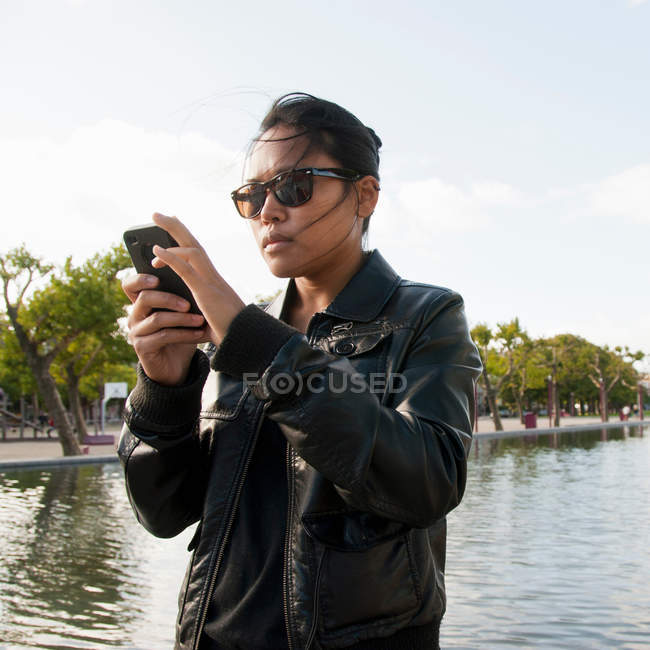 Jovem mulher em óculos de sol usando telefone celular — Fotografia de Stock
