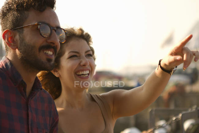 Giovane coppia che ride, donna che indica — Foto stock