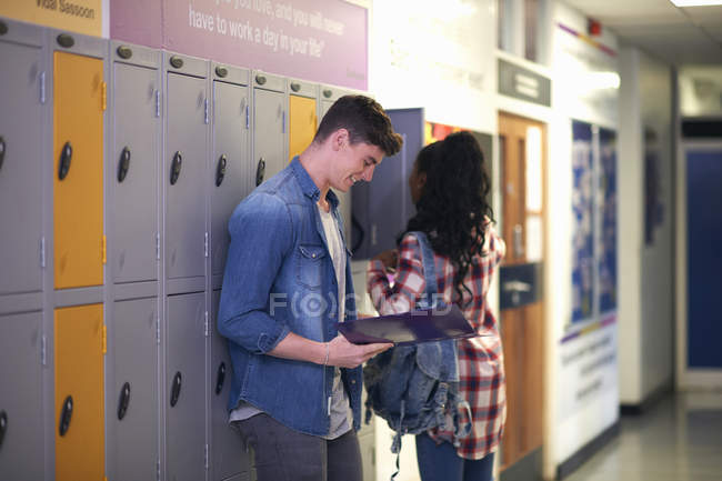 Jovem estudante do sexo masculino revisando de arquivo no vestiário da faculdade — Fotografia de Stock