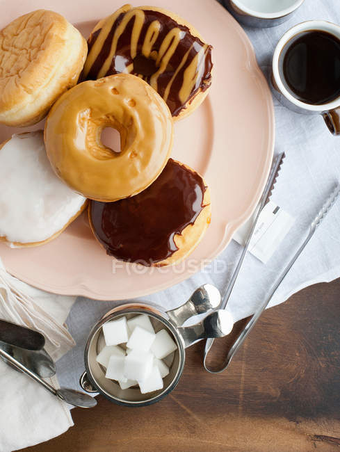 Plate of donuts with coffee and sugar — Stock Photo