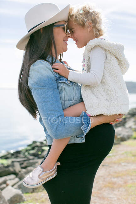 Pregnant mother face to face with daughter at coast — Stock Photo