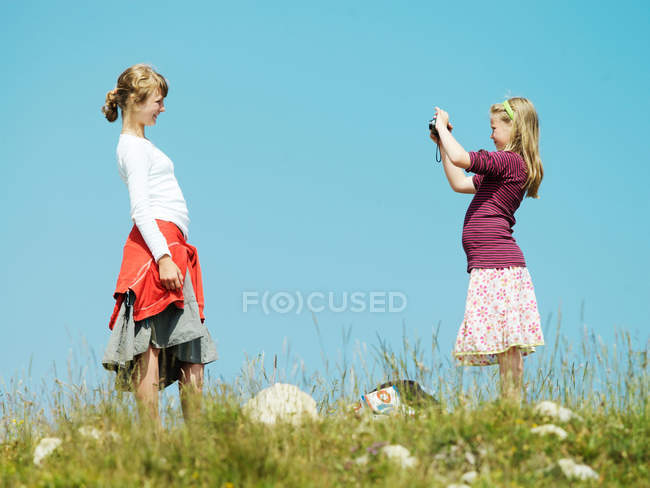 Girl taking picture of friend outdoors — Stock Photo