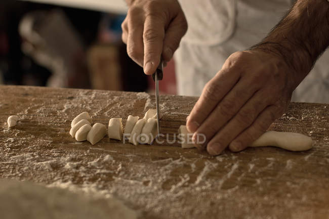 Abgeschnittenes Bild vom Koch, der Gnocchi-Teig schneidet — Stockfoto