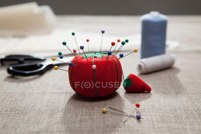 Pin cushion with threads and scissors on table — Stock Photo