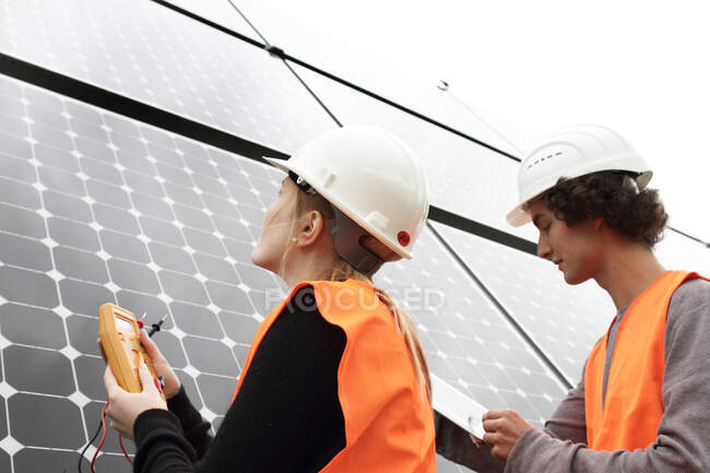 Hombre y mujer trabajando en paneles fotovoltaicos - foto de stock