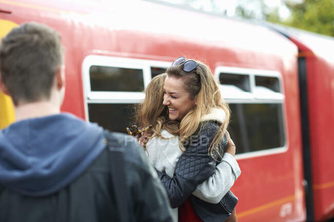 Deux amies s'embrassant à la gare, souriantes — Photo de stock