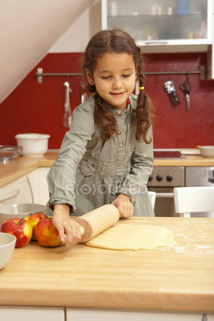 Ragazza rotolamento pasta pasticceria in cucina — Foto stock