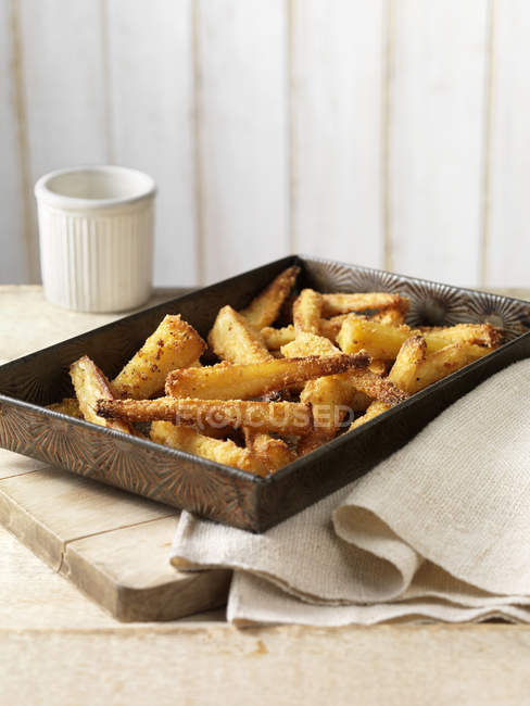 Roast parsnips with crispy seasoning in tray on table — Stock Photo