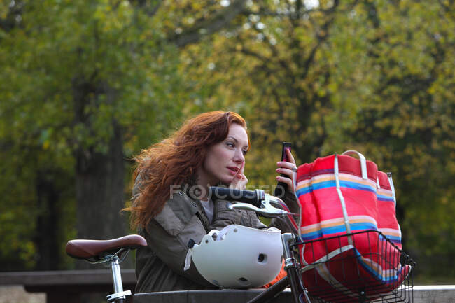 Mujer aplicando maquillaje en el parque - foto de stock