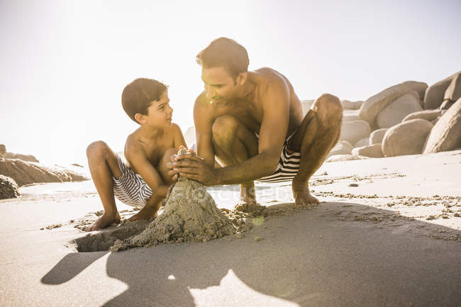 Ragazzo e padre che fanno castello di sabbia sulla spiaggia, Città del Capo, Sud Africa — Foto stock