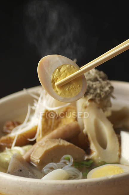 Baguettes ramasser l'oeuf dans un bol de nouilles — Photo de stock