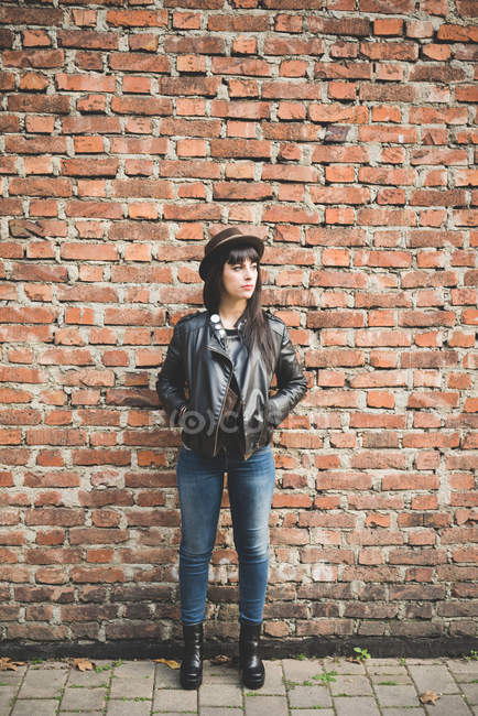 Jeune femme devant un mur de briques — Photo de stock