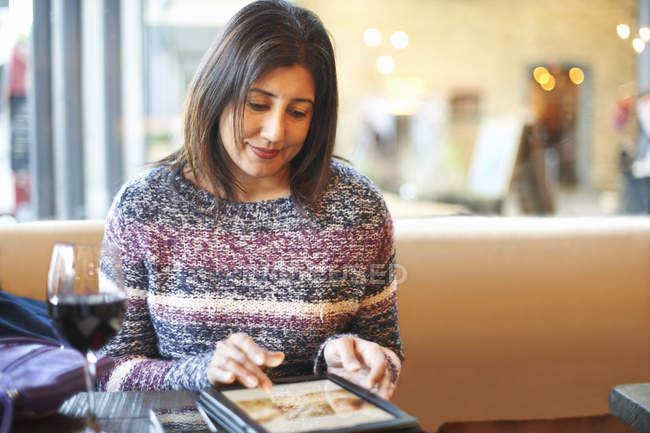 Mature woman using touchscreen on digital tablet in wine bar — Stock Photo