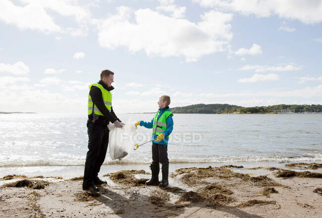 Pai e filho limpeza praia — Fotografia de Stock