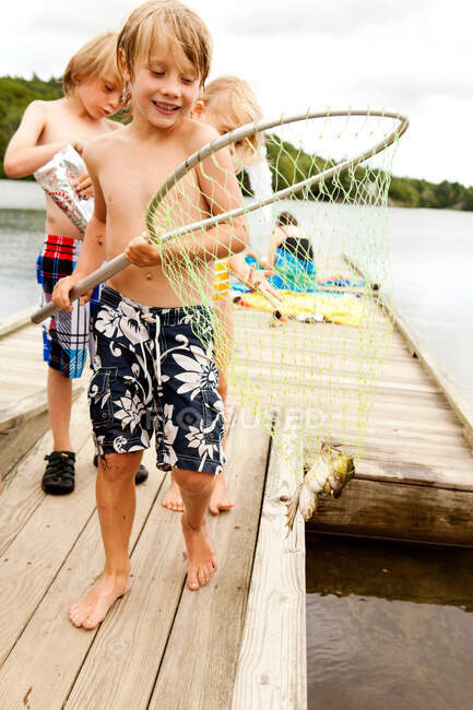 Niño con rana en una red de pesca - foto de stock