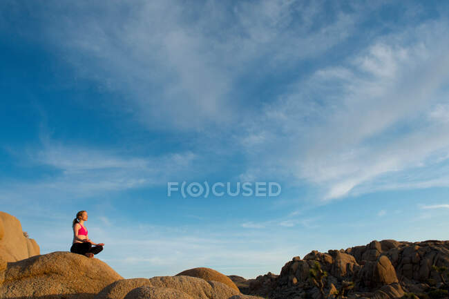 Woman meditating on desert rocks — Stock Photo