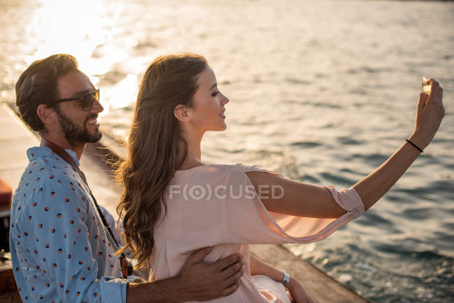 Pareja romántica tomando selfie smartphone en barco en Dubai marina, Emiratos Árabes Unidos - foto de stock