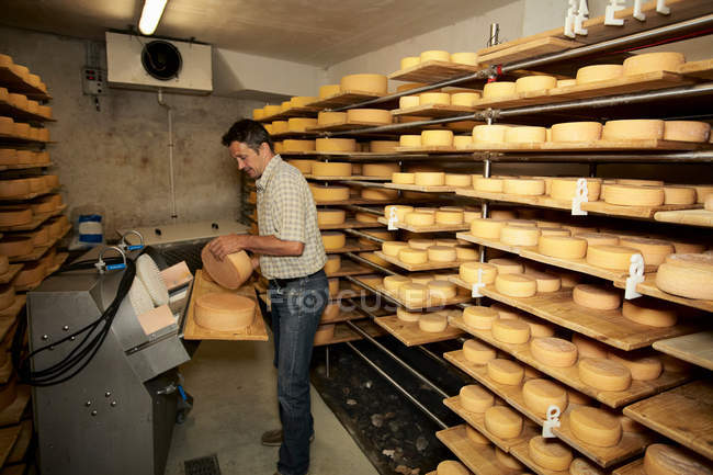 Worker finishing wheel of cheese in shop — Stock Photo