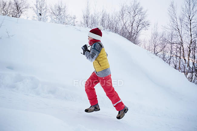 Junge rennt schneebedeckten Hügel hinauf, Hemavan, Schweden — Stockfoto