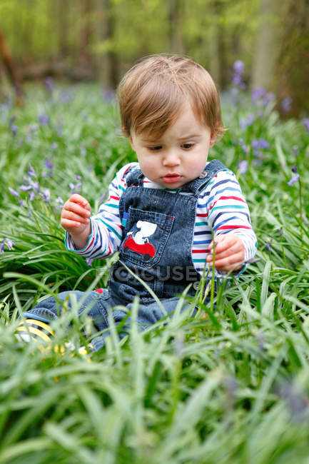 Garçon jouer avec des fleurs dans prairie — Photo de stock