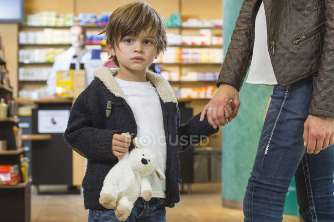 Menino e sua mãe estão procurando tratamento médico em uma farmácia — Fotografia de Stock