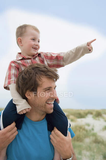 Хлопчик на плечах батька, вказуючи — стокове фото