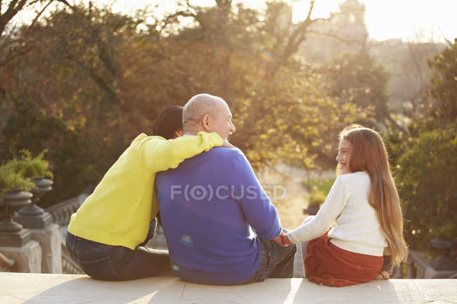 Вид ззаду чоловіка, що сидить на сходах у парку з дочкою та онукою — стокове фото