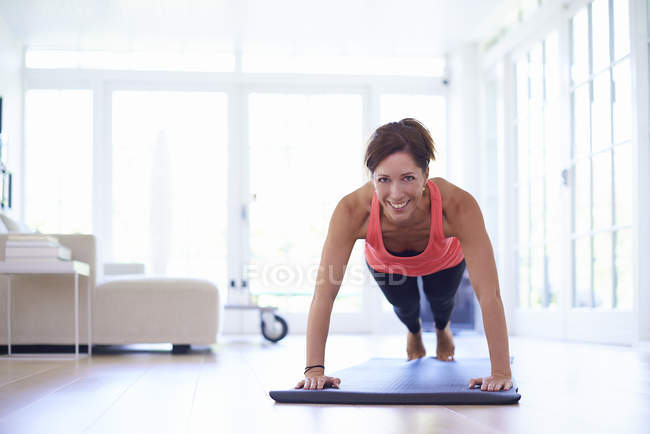 Mid adult woman doing plank pose in living room — Stock Photo