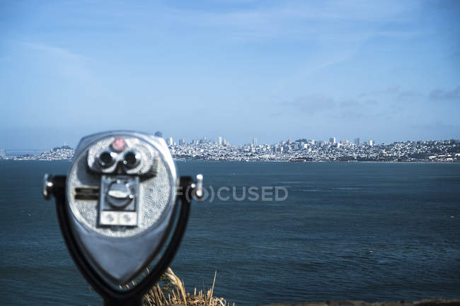 Бинокль с монетами на фоне силуэта Сан-Франциско — стоковое фото