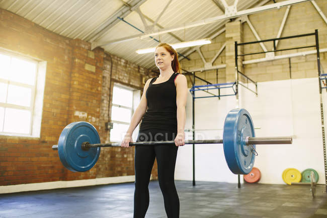Женщина поднимает штангу в спортзале — стоковое фото