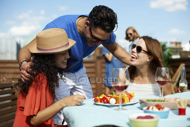 Male and female friends chatting at rooftop barbecue — Stock Photo