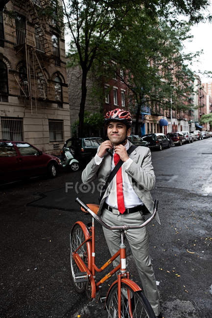 Jovem empresário ajustando capacete ciclo na rua — Fotografia de Stock