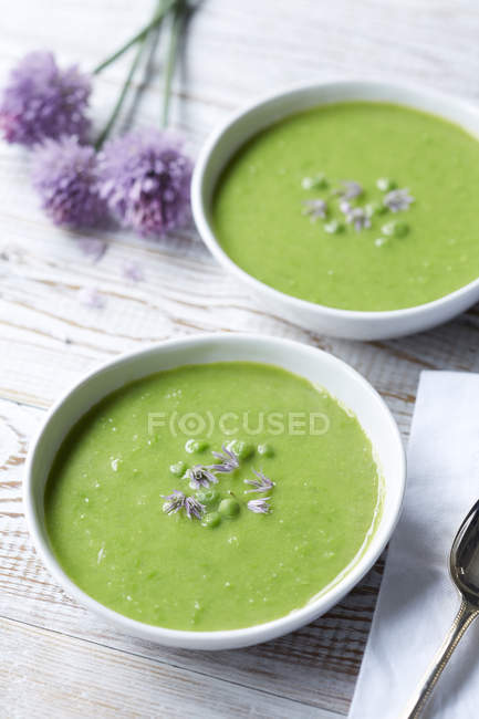 Sopa de ervilha servida com cebolinha fresca e flores de cebolinha — Fotografia de Stock