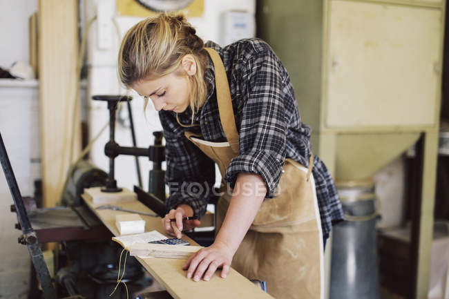 Junge Handwerkerin mit Taschenrechner in Pfeifenorgelwerkstatt — Stockfoto