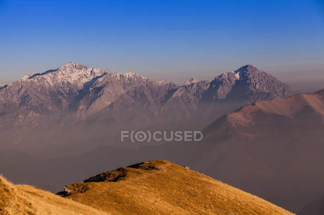 Scenic view of sun lighted hill and snowcapped mountains — Stock Photo