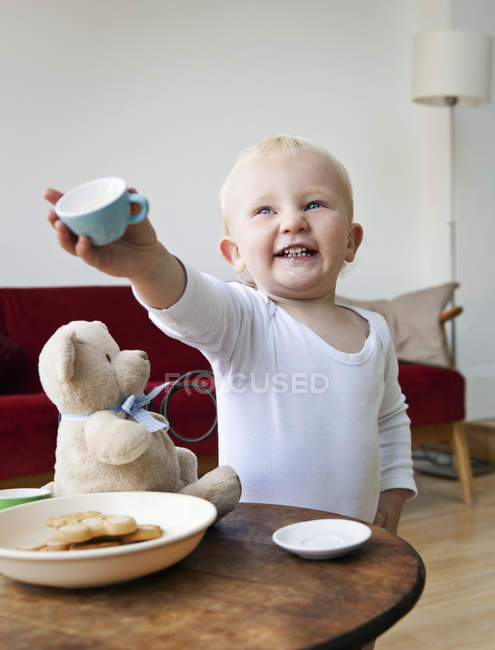 Un niño pequeño sosteniendo una taza de té - foto de stock