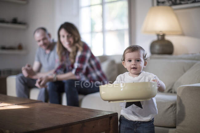Дитячий хлопчик у вітальні тримає велику чашу, дивлячись на камеру посміхаючись — стокове фото