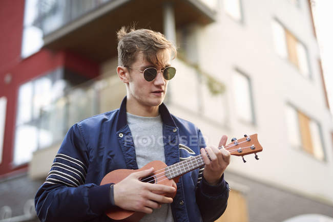 Young man on playing ukulele on street — Stock Photo