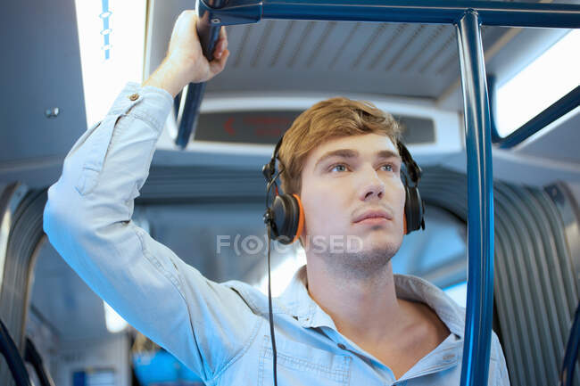 Молодой человек в вагоне поезда слушает наушники — стоковое фото