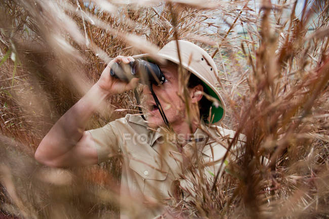 Man in jungle outfit using binoculars — Stock Photo