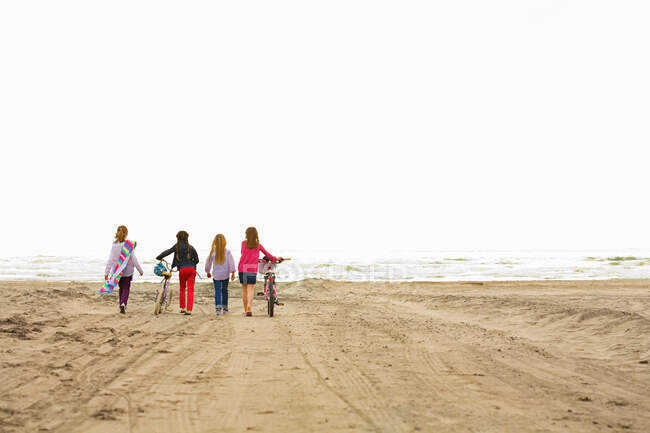 Девочки, гуляющие по песку на пляже — стоковое фото