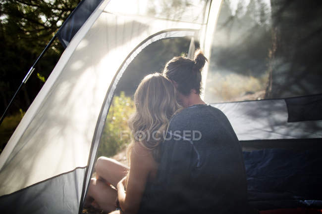 Young couple looking out from sunlit tent, Lake Tahoe, Nevada, USA — Stock Photo