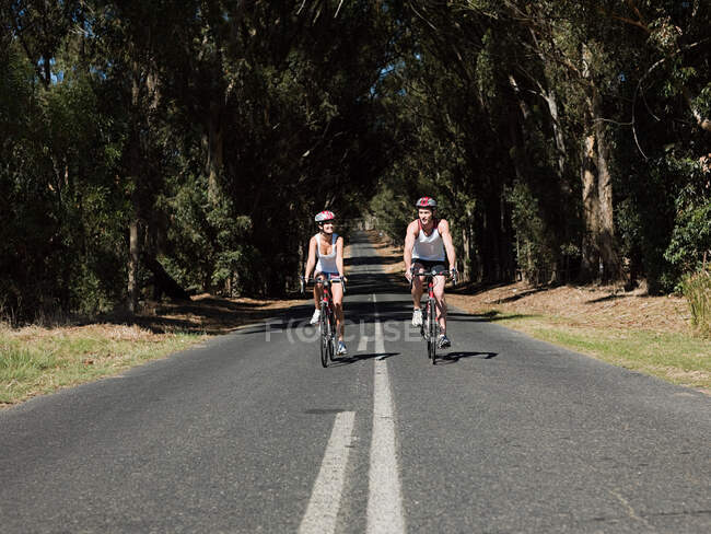 Jovem casal de ciclismo na estrada — Fotografia de Stock