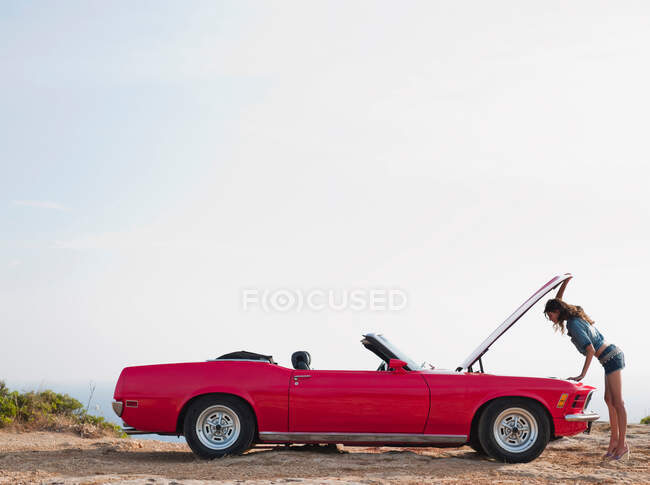 Женщина смотрит в открытую капот автомобиля — стоковое фото