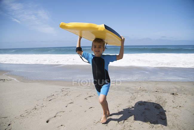 Boy running on beach and carrying bodyboard, Laguna Beach, California, USA — Stock Photo