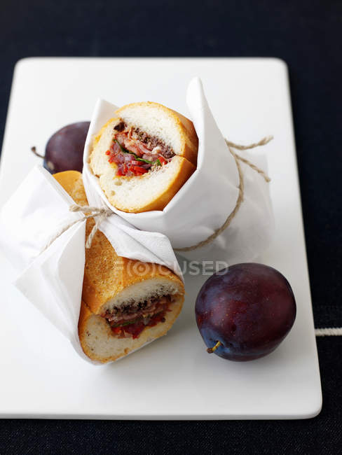 Plate of plums with sandwiches — Stock Photo