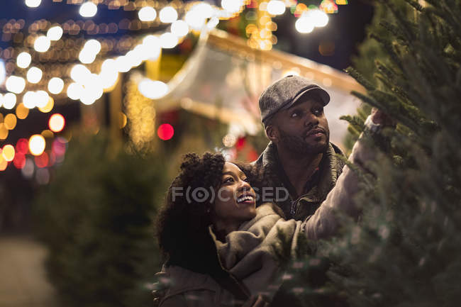 Casal feliz romântico desfrutando da cidade durante as férias de inverno olhando para árvores de Natal — Fotografia de Stock